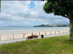 een man op een bankje naast het strand bij Apartamento a pie de playa en Miño in Miño