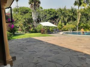 um pátio com uma mesa e um guarda-sol ao lado de uma piscina em Cuernavaca Eden Hotel Boutique doble em Cuernavaca