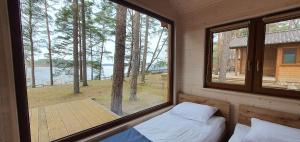 a bedroom with a window with a view of a lake at Domki Borsk - nad samym jeziorem, nowe w pełni wyposażone z miejscem parkingowym in Borsk