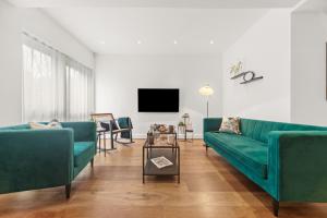 a living room with two green couches and a tv at Springfield Two in Harrogate