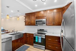 プラヤ・フラミンゴにあるStylish 2-Bedroom Beach Condo with Ocean-View Deck, Lush Pool Area & 2-Minute Walk to Flamingo Beachのキッチン(木製キャビネット、ステンレス製の冷蔵庫付)