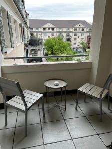 einen Balkon mit 2 Stühlen, einem Tisch und einem Fenster in der Unterkunft Living Apartments Ludwigshafen in Ludwigshafen am Rhein