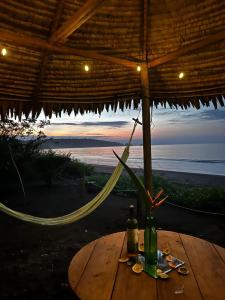 Una mesa con una sombrilla de paja y una botella encima. en Ecohotel Luzul, en Nuquí