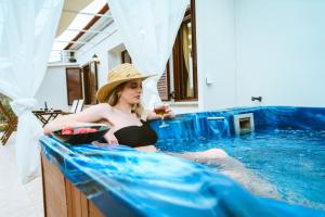 kobieta siedząca w basenie z kieliszkiem wina w obiekcie Erotokritos Deluxe Suite With Jacuzzi w mieście Perivólia