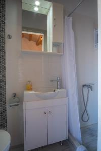 a white bathroom with a sink and a mirror at A window to the Aegean in Kokkari