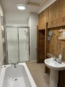 La salle de bains est pourvue d'une baignoire, d'un lavabo et d'une douche. dans l'établissement Beech cottage ~ close to York ~ cozy rural stay, à Stamford Bridge
