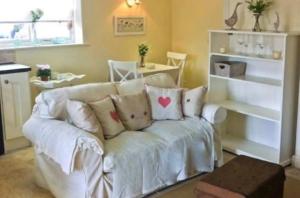 - un salon avec un canapé blanc et des oreillers dans l'établissement Beech cottage ~ close to York ~ cozy rural stay, à Stamford Bridge