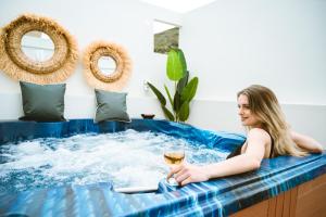 kobieta siedząca w wannie z hydromasażem i szklanką wina w obiekcie Erotokritos Deluxe Suite With Jacuzzi w mieście Perivólia