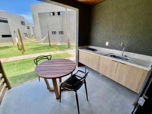 eine Küche mit einem Tisch und einem Waschbecken sowie einem Tisch und Stühlen in der Unterkunft Villas Manatee Milagres C006 in Pôrto de Pedras