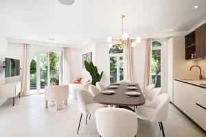 Il comprend une cuisine et une salle à manger avec une table et des chaises blanches. dans l'établissement VILLA DES PERGOLAS au pied du TRAM ,à 5 min des plages , 15 min du Centre , jacuzzi, à Nice