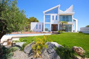 una gran casa blanca con un patio con rocas en Macarius, en Jávea