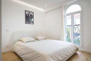 a white bedroom with a bed and a window at VILLA DES PERGOLAS 6 Ch au pied du TRAM ,à 5 min des plages , 15 min du Centre , jacuzzi in Nice