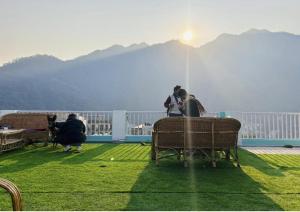 a group of people sitting on a balcony with the sun shining at The Anand with Ganga View and Rooftop Cafe in Rishīkesh