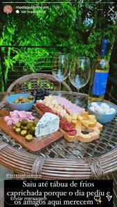 una mesa cubierta con queso, copas de vino y comida en Casa Maikäfer en Rodeio