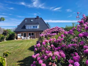 una casa con flores rosas delante de ella en Haus Westsee EG mit Garten, en Wenningstedt
