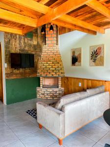 a living room with a couch and a brick fireplace at Pousada Rural Pavão in Urubici