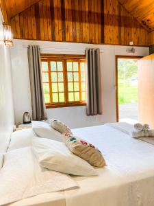 1 cama blanca grande en una habitación con ventana en Pousada Rural Pavão, en Urubici