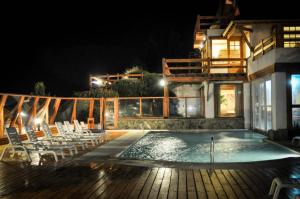 una piscina con sillas y una casa por la noche en Apart del Lago en San Carlos de Bariloche