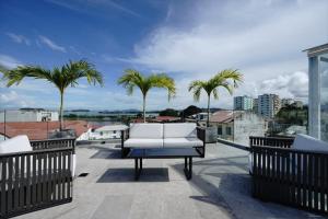 a white couch on a balcony with palm trees at Charming 2BR With Pool in Casco Antiguo in Panama City
