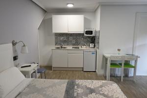 una pequeña cocina blanca con cama y mesa en Apartamentos La Cueva - Onis, en Avín