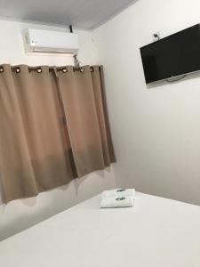 um quarto com uma cama com uma cortina e uma televisão em Hospedagem De Ferias em Bonito