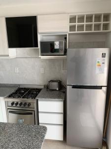 Una cocina con refrigerador de acero inoxidable y microondas. en Rio Victoria, en Victoria