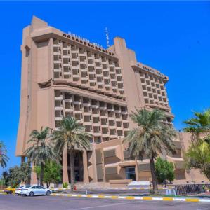 un gran edificio con palmeras delante en Almansour Hotel en Bagdad