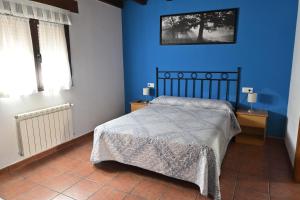 1 dormitorio azul con 1 cama y 2 ventanas en Apartamentos Aires De Avin - Onis, en Avín