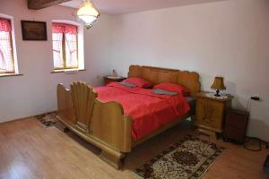 Un dormitorio con una gran cama de madera con sábanas rojas. en Salaš Trikić en Aleksandrovo