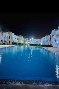 una gran piscina azul por la noche con edificios en Appartement Bousaid, en Oualidia