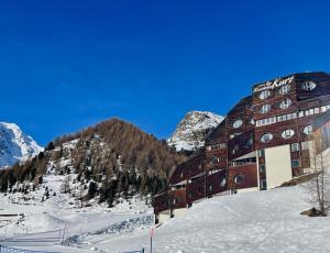 un bâtiment dans la neige avec une montagne dans l'établissement Maso Corto Alpine Adventure, à Maso Corto