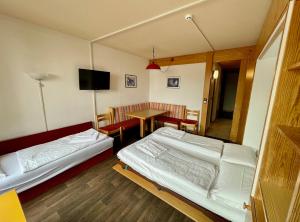 Cette chambre comprend deux lits, une table et une télévision. dans l'établissement Maso Corto Alpine Adventure, à Maso Corto