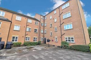 un aparcamiento vacío frente a un edificio de ladrillo en Stylish Pride Park DERBY Apartment - Free WIFI, Parking en Derby