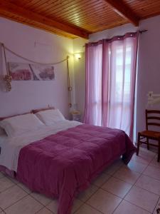 ein Schlafzimmer mit einem großen Bett mit einer lila Decke in der Unterkunft Bed and Breakfast Cala Luna in Castelsardo