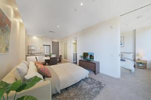 a bedroom with a large bed and a living room at A Comfy & Central 2BR Apt Near Flinders Station in Melbourne