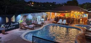 a pool at night with a bar and a restaurant at Terra Iguazú Cabañas in Puerto Iguazú