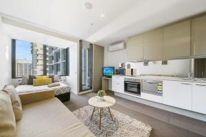 a kitchen and living room with a couch and a table at A Charming Studio with Stunning City Views in Melbourne