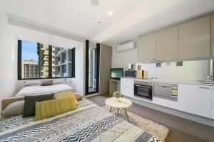 a bedroom with a king sized bed and a kitchen at A Charming Studio with Stunning City Views in Melbourne