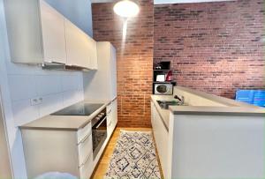 a kitchen with white cabinets and a brick wall at Centre ville Bruxelles/ Bruxelles City Center in Brussels