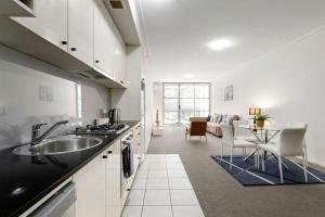 a kitchen with a sink and a living room at A Modern & Cozy Studio Next to Darling Harbour in Sydney
