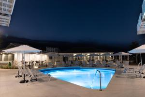 a swimming pool with chairs and umbrellas at night at South Point Hotel in Christ Church