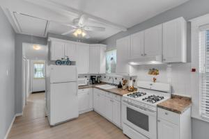 a white kitchen with white appliances and a ceiling fan at Short Walk to the Beach! in Keansburg