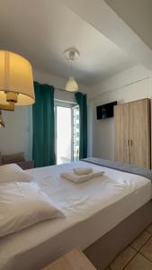 a large white bed in a room with a window at Hotel Ionion in Piraeus