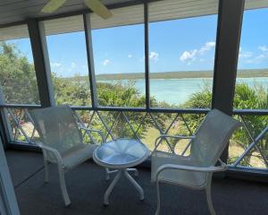 duas cadeiras e uma mesa num quarto com vista para o oceano em Sunnyside home em Savannah Sound