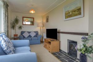 ein Wohnzimmer mit einer blauen Couch und einem Fernseher in der Unterkunft The Quillet in Penzance