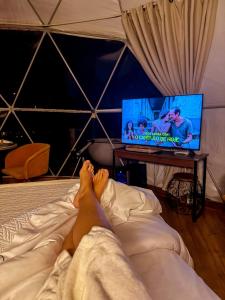 a person laying on a bed watching a tv at Glamping Atmosphera in Cambara do Sul +30 photos