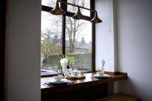 een tafel met kopjes en schotels voor een raam bij Slaymaker Cottage in Oakworth