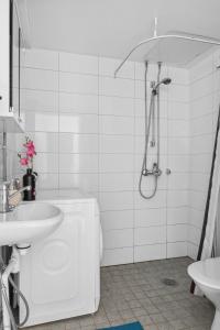 uma casa de banho branca com um chuveiro e um lavatório. em Happy house em Helsínquia