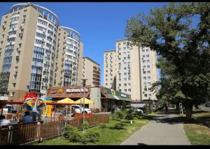 twee hoge gebouwen in een stad met een park bij Студия Свежесть в центре города in Alma-Ata