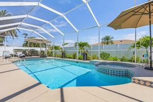 a large swimming pool with an umbrella and a swimming poolvisor at Villa-Haze, lots of privacy, solar & electric heated pool and SPA in Cape Coral